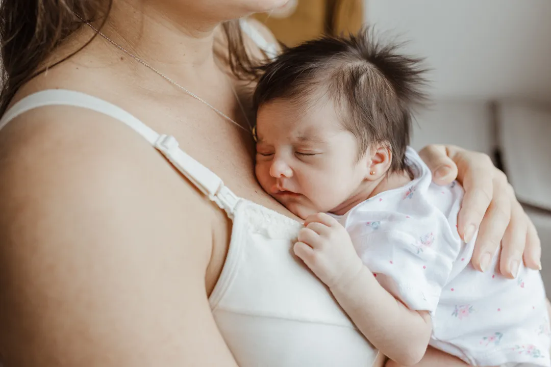 Ein schlafendes Neugeborenes liegt auf der Brust seiner Mutter.