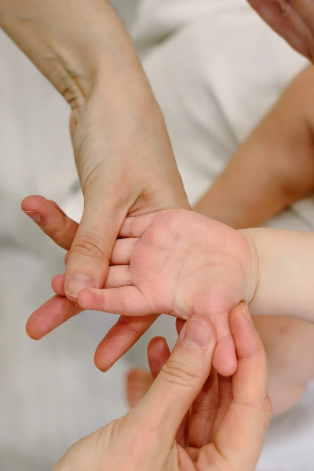 Eine erwachsene Hand massiert die geöffnete Hand eines Babys.