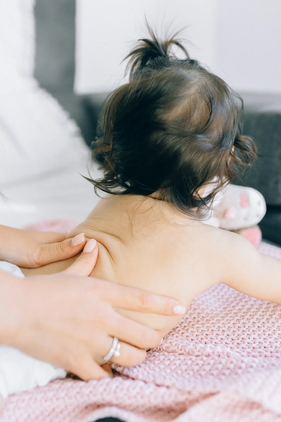 Eine Hand liegt flach auf dem Rücken eines Babys.